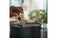 A person placing a capsule-free coffee ball into a coffee maker.